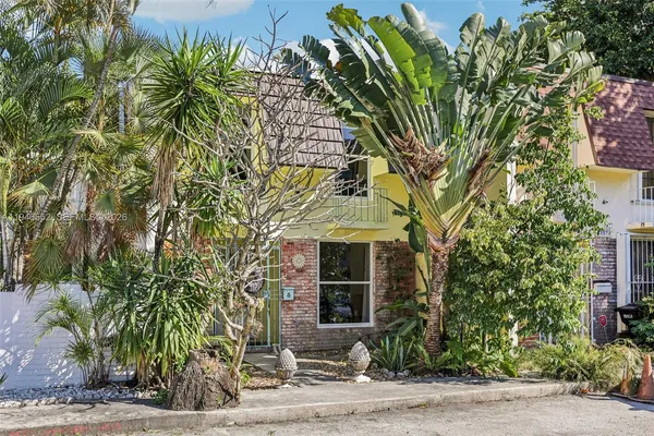 a front view of a house with a tree
