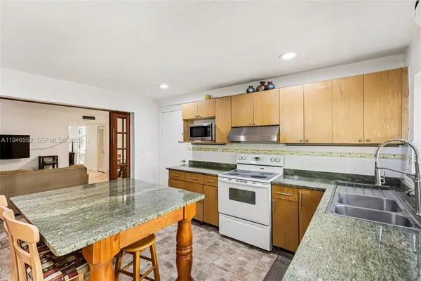 a kitchen with stainless steel appliances granite countertop a table chairs and a refrigerator