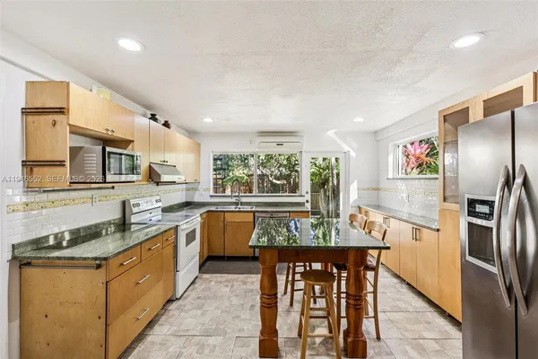 a kitchen with kitchen island granite countertop a stove top oven a sink a counter space and cabinets