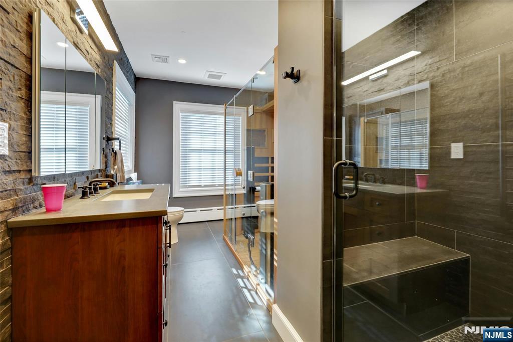 292 Maple Street Englewood, NJ 07631 - Photo 27 of 48 a view of a bathroom with a tub sink mirror and shower