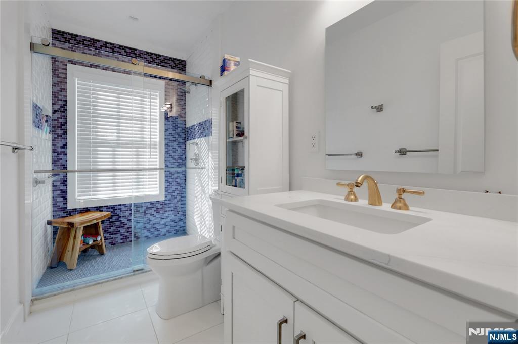 292 Maple Street Englewood, NJ 07631 - Photo 35 of 48 a bathroom with a sink a toilet and a large mirror