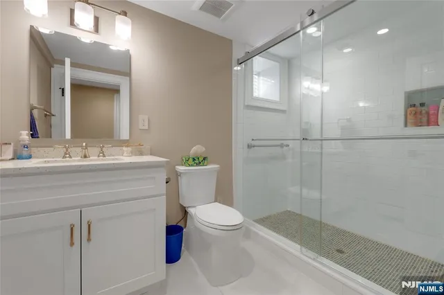 a bathroom with a sink a toilet a mirror and shower