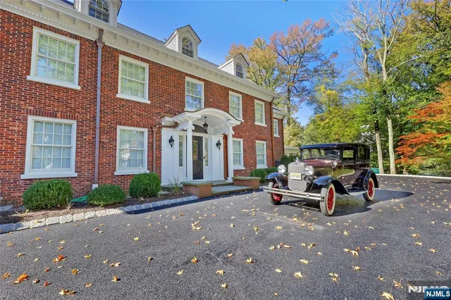 a view of a brick house with many windows and a table and chairs under an umbrella
