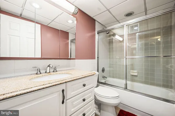 a bathroom with a granite countertop toilet sink shower and mirror