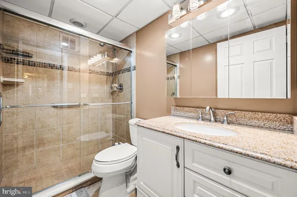 a bathroom with a granite countertop sink toilet mirror and shower