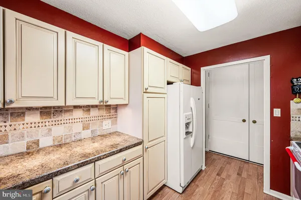 a kitchen with granite countertop white cabinets and refrigerator