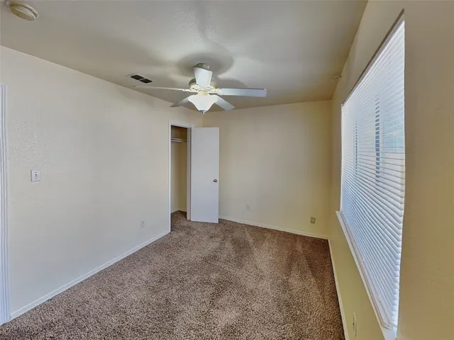 an empty room with a ceiling fan and carpet