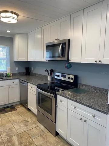 a kitchen with granite countertop white cabinets and stainless steel appliances