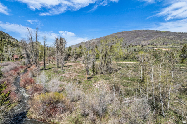 6314 Stewart Ranch Road Kamas, UT 84036 - Photo 4 of 10 Expansive natural landscape featuring a flowing creek, diverse mature trees, and a distant mountainous backdrop under a clear blue sky