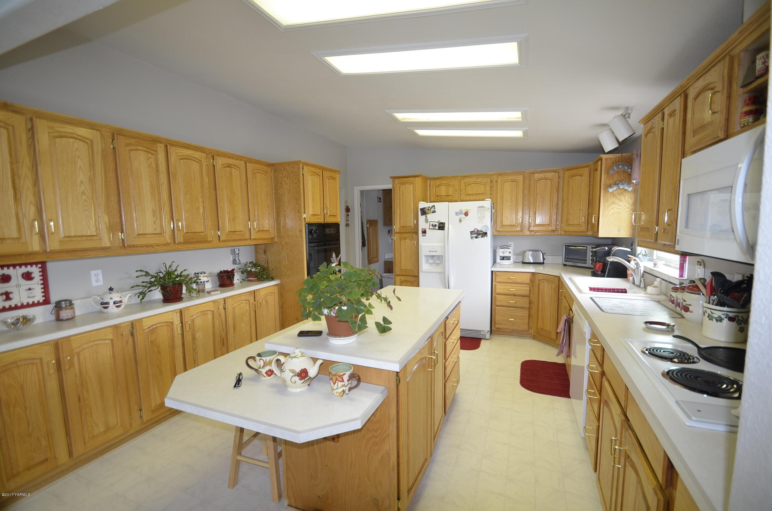 1454 Konnowac Pass Road Moxee, WA 98936 - Photo 5 of 34 a kitchen with refrigerator a stove a sink and white cabinets with wooden floor