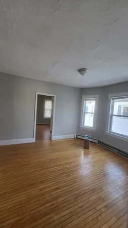 an empty room with wooden floor and window