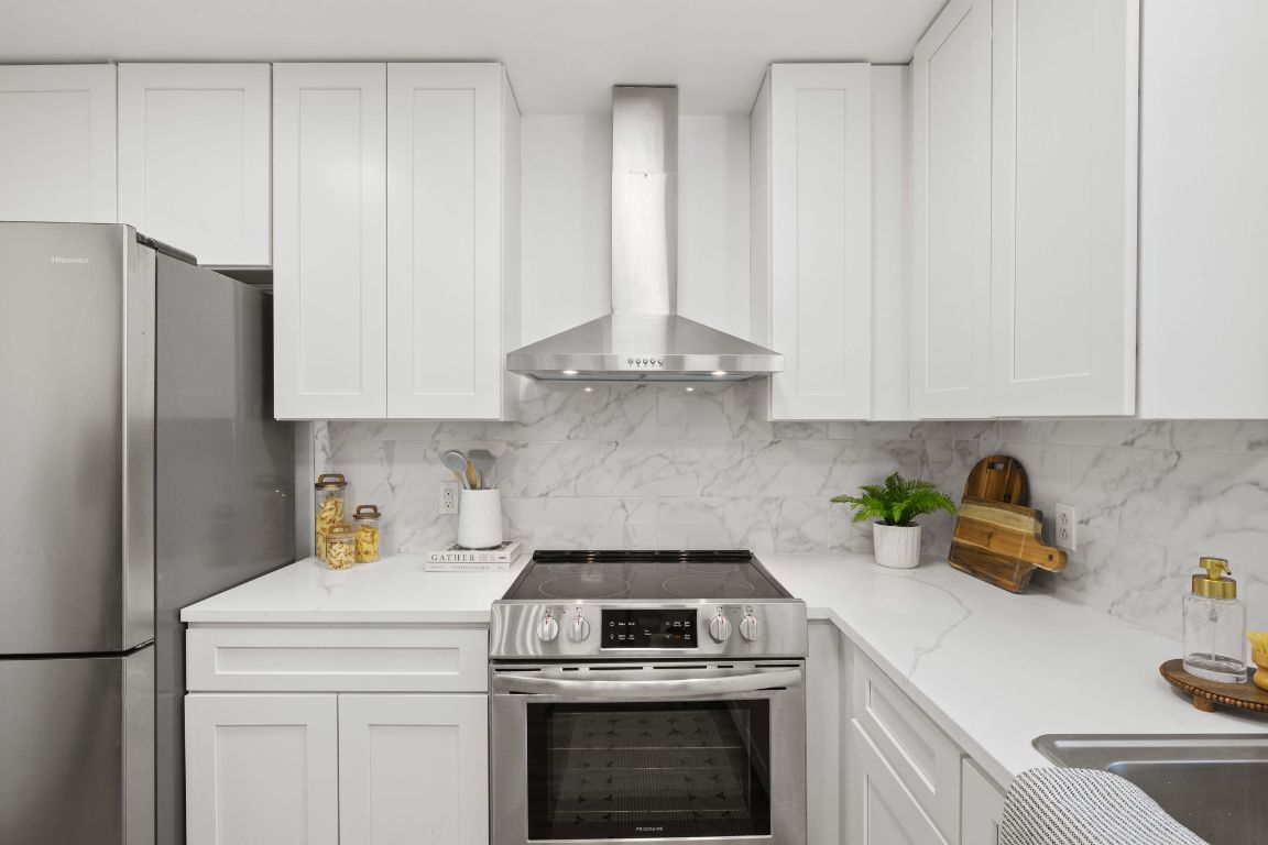 902 Virginia Drive Round Rock, TX 78664 - Photo 13 of 33 a kitchen with a stove and white cabinets