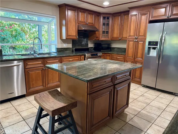 a kitchen with stainless steel appliances granite countertop a stove a sink a microwave a refrigerator and cabinets