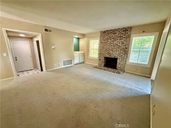 a view of an empty room with a fireplace and a window