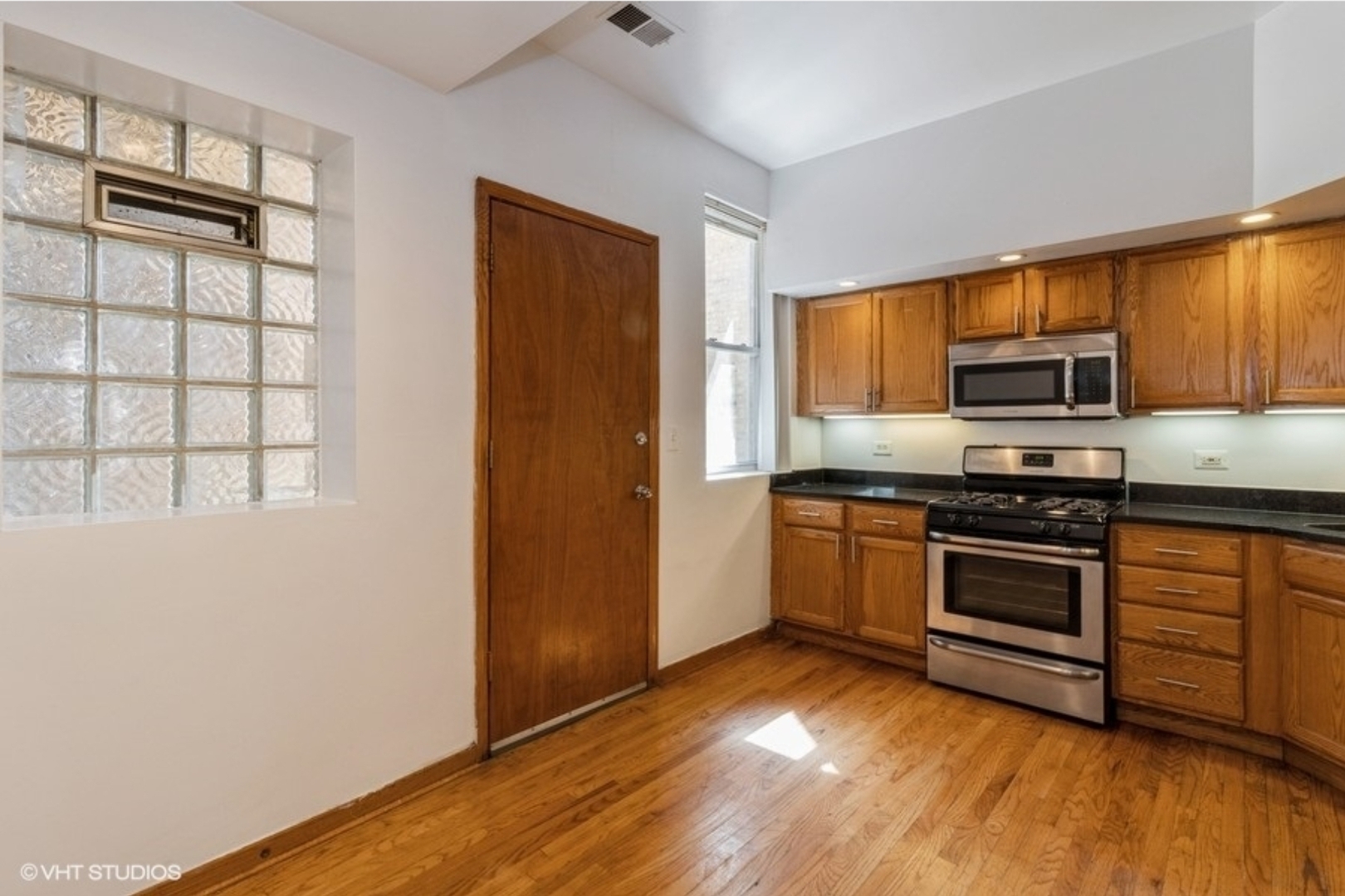 Undisclosed Address Chicago, IL 60647 - Photo 3 of 15 a kitchen with granite countertop wooden floors and stainless steel appliances