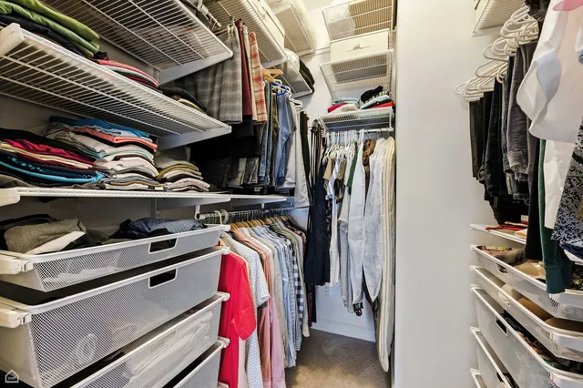 a view of walk in closet with clothes and shoes