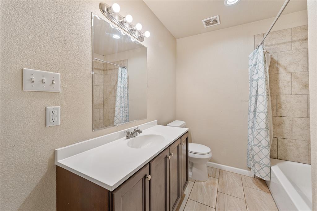 409 Morgan Mill Road Stephenville, TX 76401 - Photo 12 of 25 a bathroom with a sink a toilet a mirror and shower