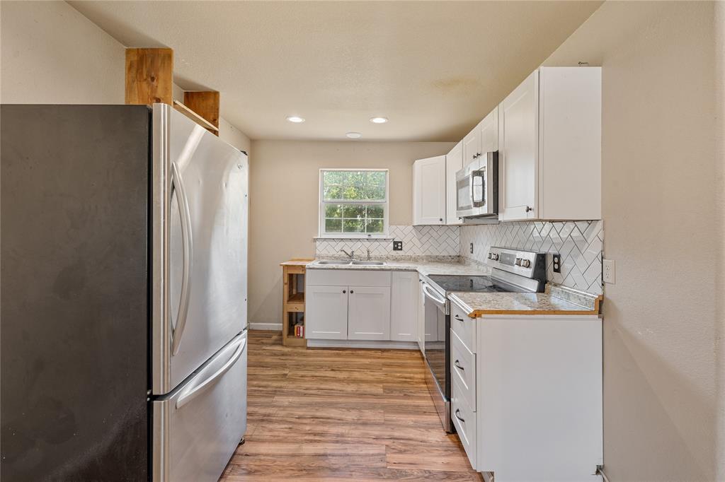 409 Morgan Mill Road Stephenville, TX 76401 - Photo 7 of 25 a kitchen with a sink stove and refrigerator