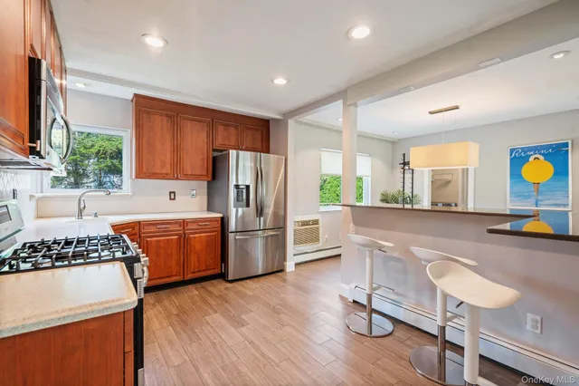 a kitchen with stainless steel appliances granite countertop a stove a refrigerator a sink a dining table and chairs with wooden floor