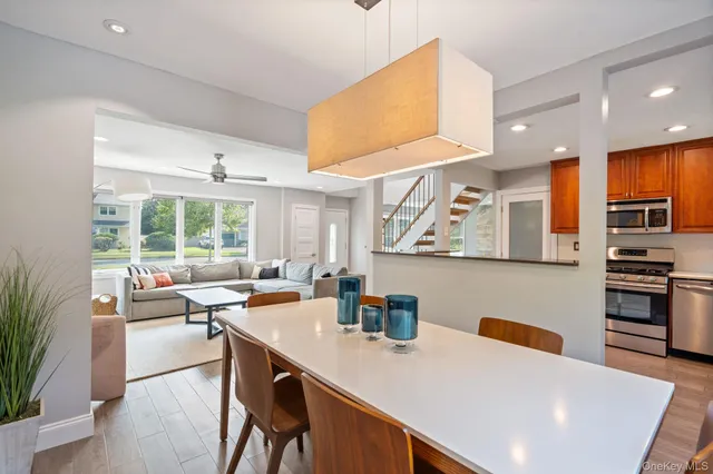 a living room with stainless steel appliances kitchen island granite countertop a table chairs sink and cabinets