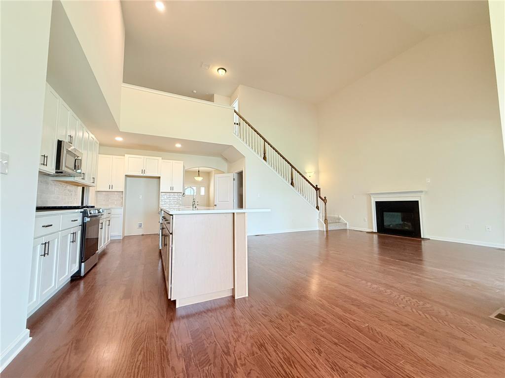 328 Abby Road, Unit LOT 15 Macungie, PA 18062 - Photo 21 of 26 A spacious great room showcasing soaring ceilings, a corner fireplace, and an inviting open-concept kitchen.