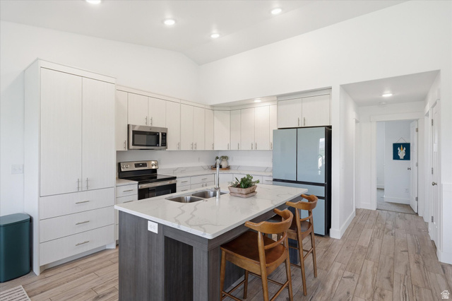 1422 West 3410th Street South Logan, UT 84321 - Photo 8 of 33 Modern kitchen featuring an expansive center island with dual sinks and seating, sleek white cabinetry, stainless steel appliances, and wood-finish flooring