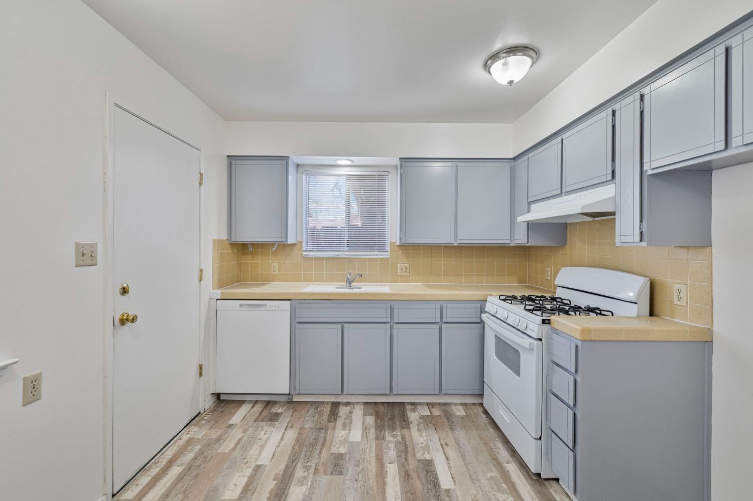 1520 South Reed Avenue Reedley, CA 93654 - Photo 9 of 20 a kitchen with a sink a stove cabinets and a wooden floor