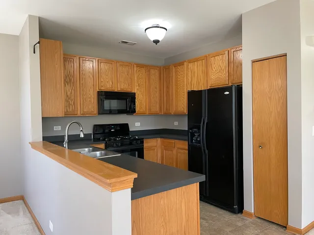 a kitchen with granite countertop wooden cabinets a refrigerator and a sink