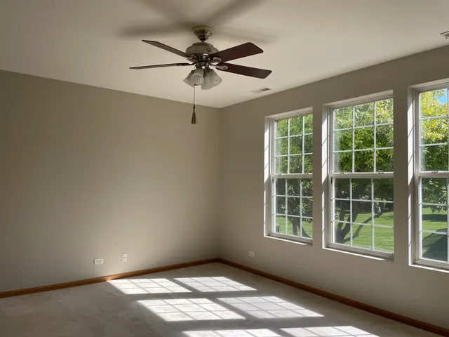 an empty room with windows and fan