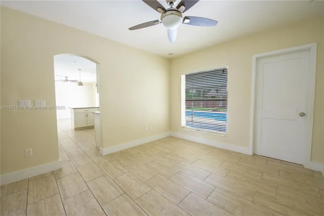 a view of an empty room with window and chandelier fan
