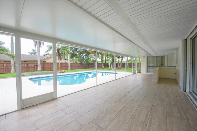 a view of an empty room with a floor to ceiling window next to a yard