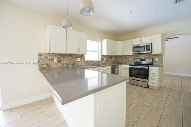 a kitchen with stainless steel appliances granite countertop a stove a sink and a refrigerator