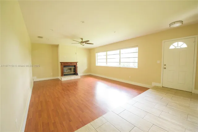 a view of empty room with a fireplace and wooden floor