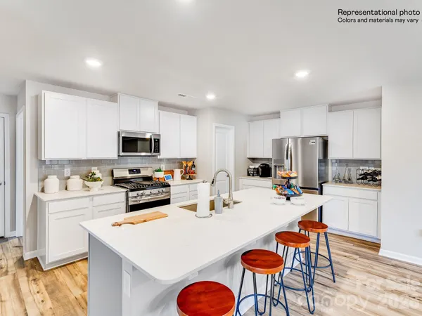 a kitchen with stainless steel appliances a refrigerator a stove a microwave a dining table and chairs with wooden floor