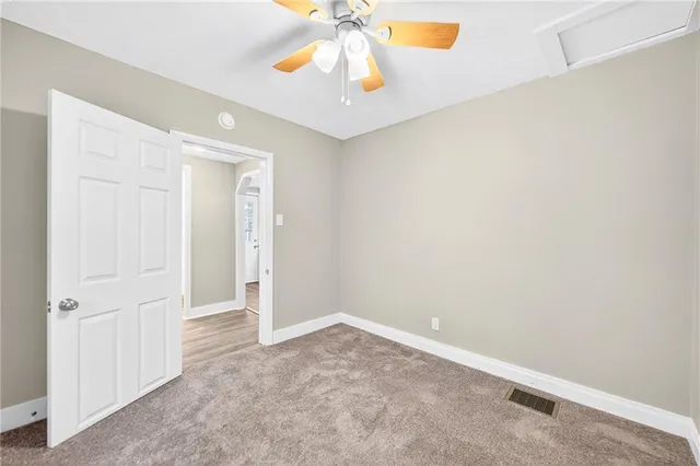 an empty room with a chandelier fan and a window