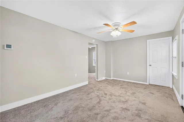 an empty room with closet and a ceiling fan