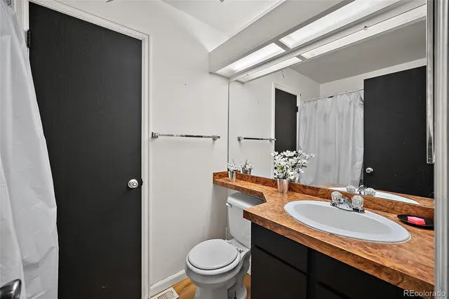 a bathroom with a granite countertop sink toilet and a mirror