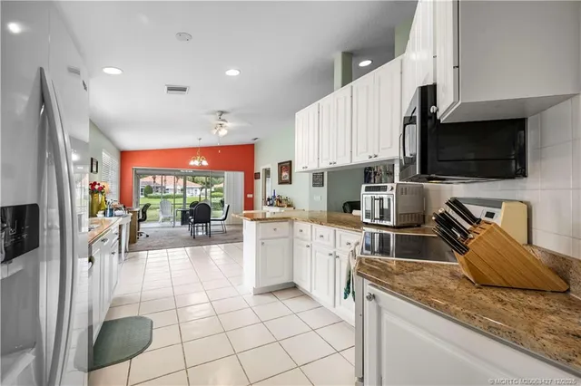 a kitchen with stainless steel appliances granite countertop a sink a stove top oven a granite counter tops and white cabinets