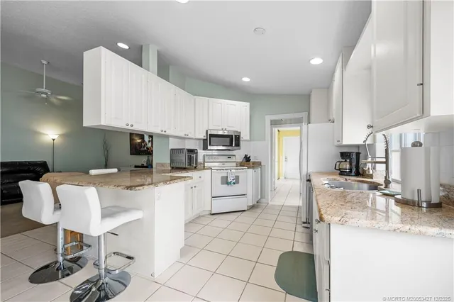 a kitchen with granite countertop a sink appliances cabinets and furniture