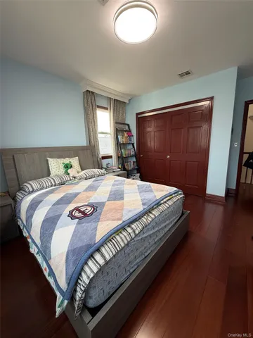 a bedroom with a bed and dresser with wooden floor