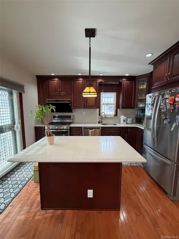 a kitchen with stainless steel appliances granite countertop a refrigerator a stove and a sink with wooden floors