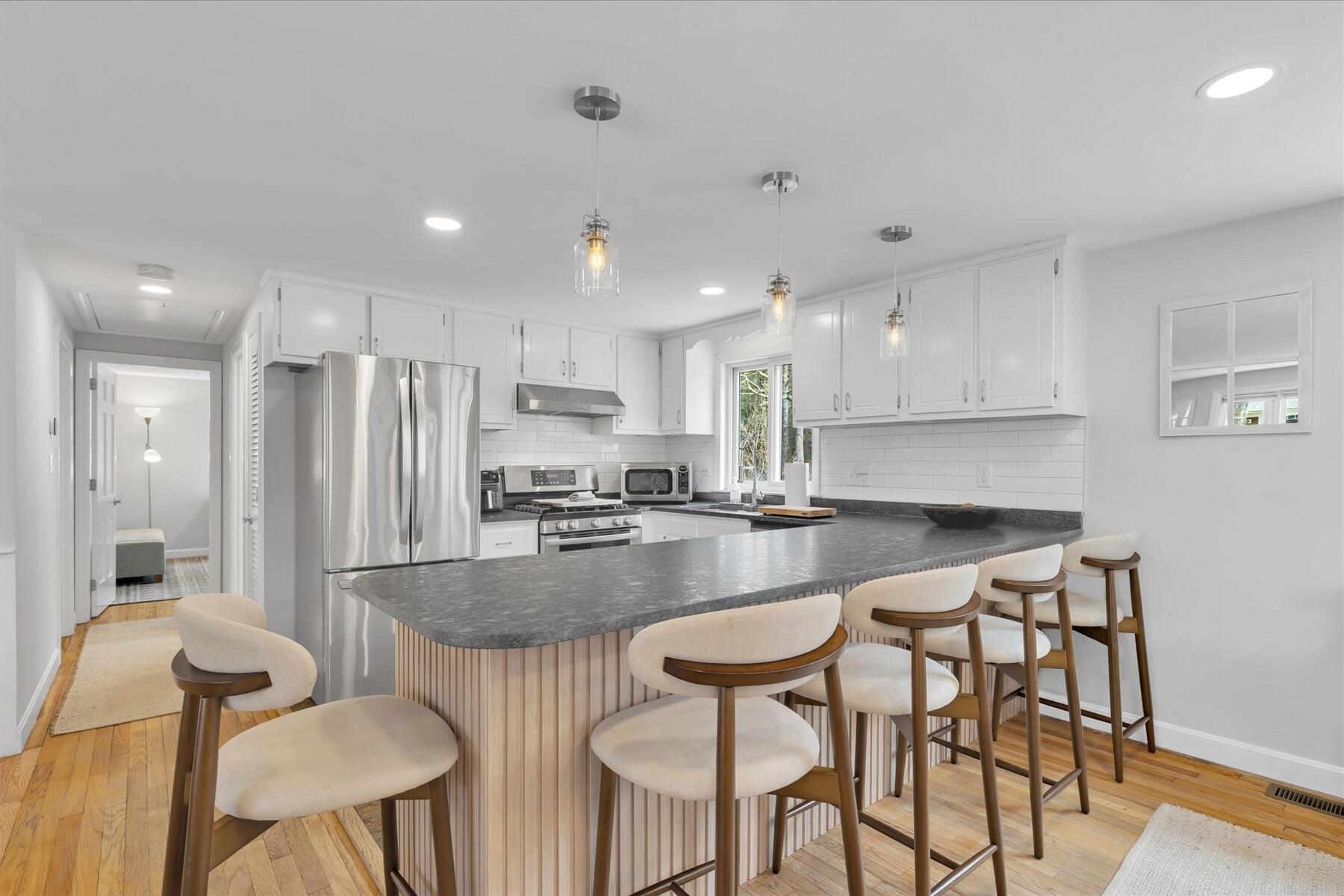 80 Coolidge Road West Yarmouth, MA 02673 - Photo 14 of 37 a kitchen with stainless steel appliances granite countertop a table chairs sink refrigerator and microwave