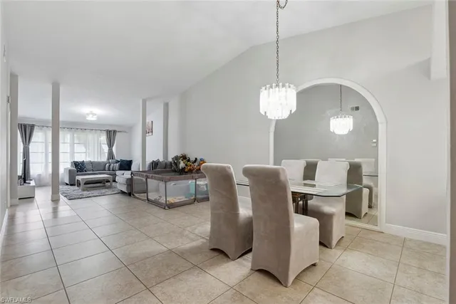 a living room with couches a table and chairs with kitchen view