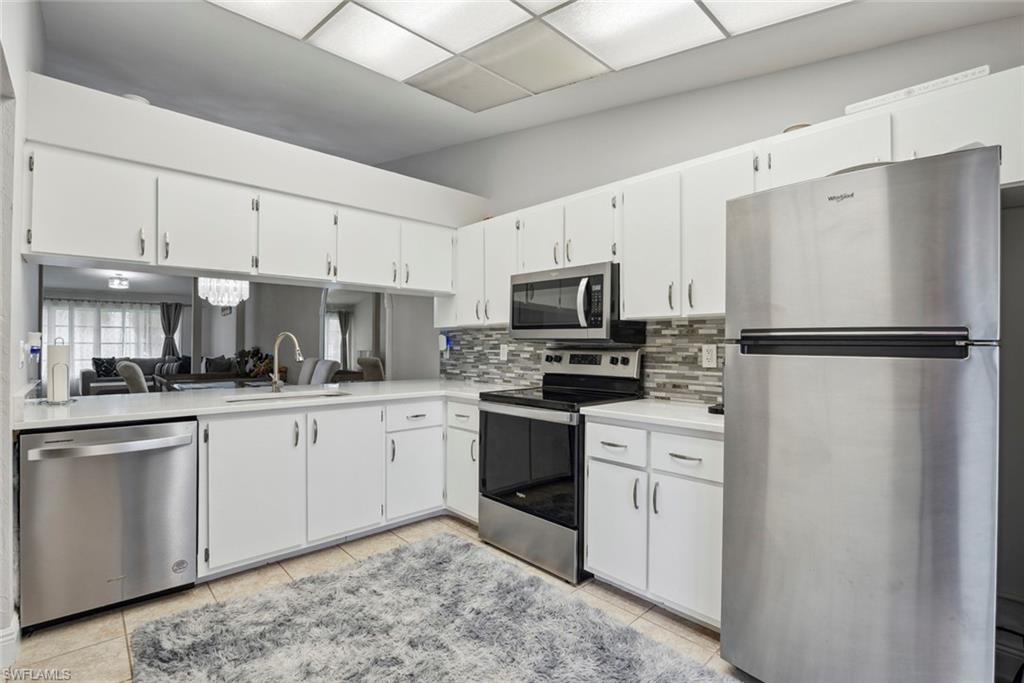 3410 Frosty Way, Unit 4802 Naples, FL 34112 - Photo 16 of 27 Kitchen featuring stainless steel appliances, a sink, light countertops, decorative backsplash, and light tile patterned flooring