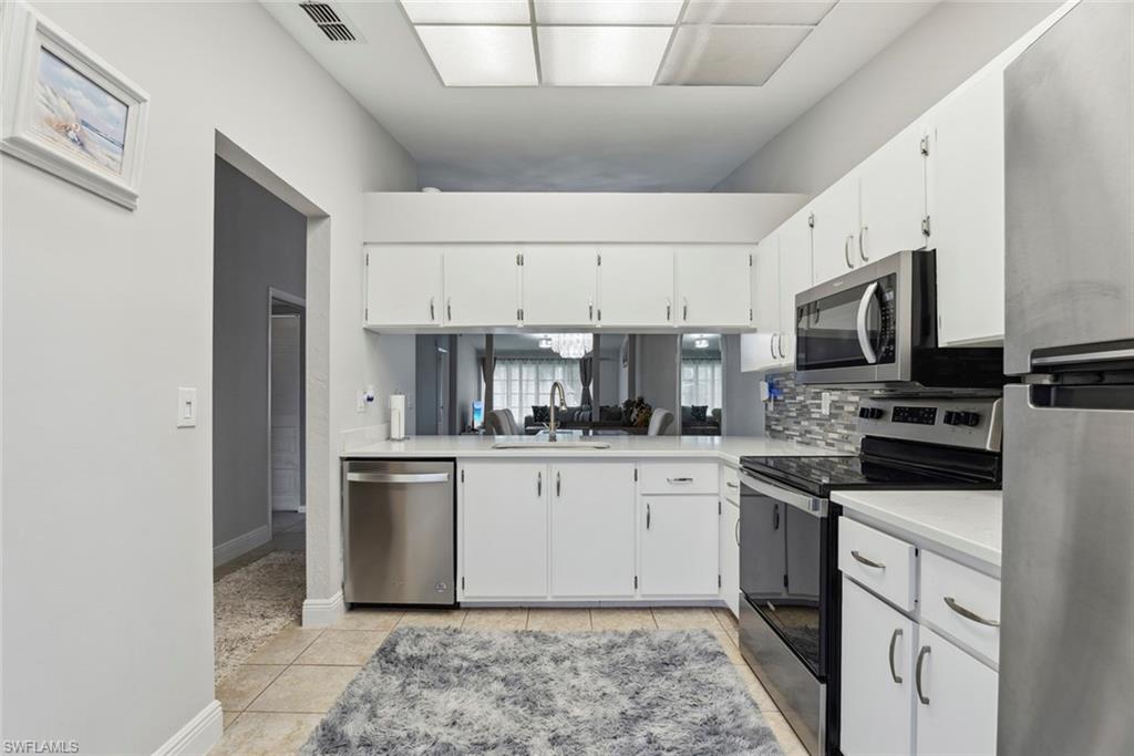 3410 Frosty Way, Unit 4802 Naples, FL 34112 - Photo 3 of 27 Kitchen featuring appliances with stainless steel finishes, a sink, light countertops, and white cabinetry