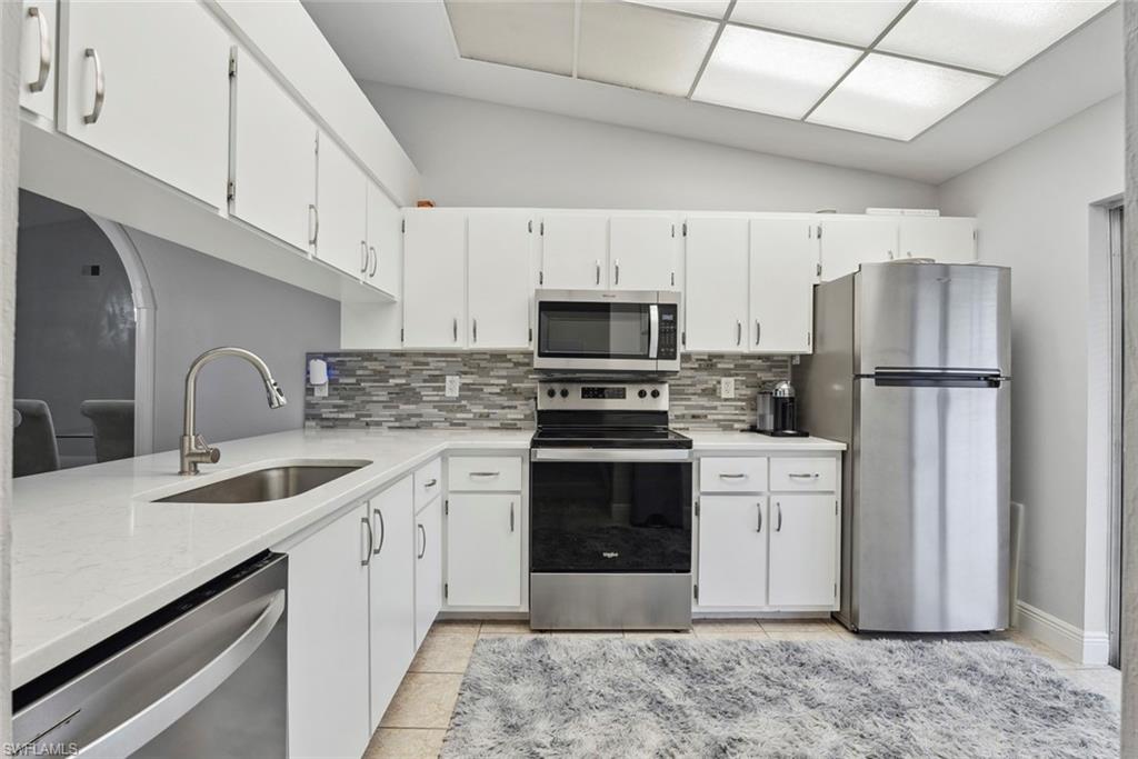 3410 Frosty Way, Unit 4802 Naples, FL 34112 - Photo 6 of 27 Kitchen featuring stainless steel appliances, a sink, quartz countertops, backsplash, and light tile patterned floors