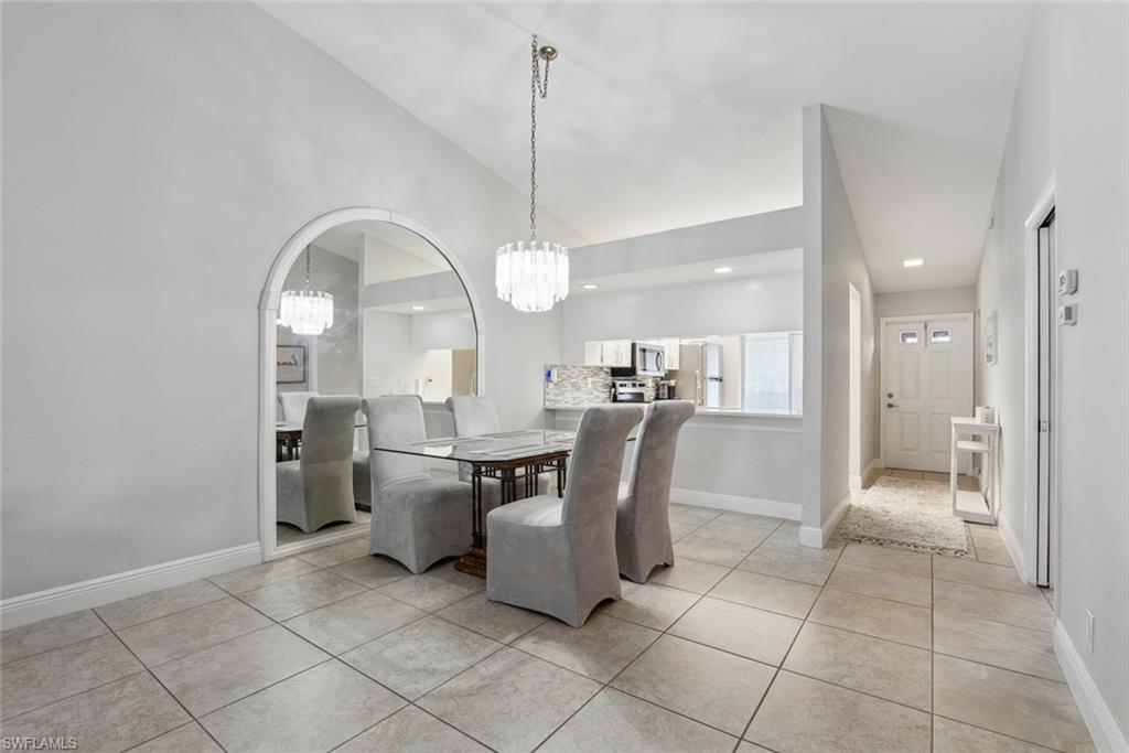 3410 Frosty Way, Unit 4802 Naples, FL 34112 - Photo 7 of 27 Dining room with a chandelier, light tile patterned floors, baseboards, vaulted ceiling, and arched walkways