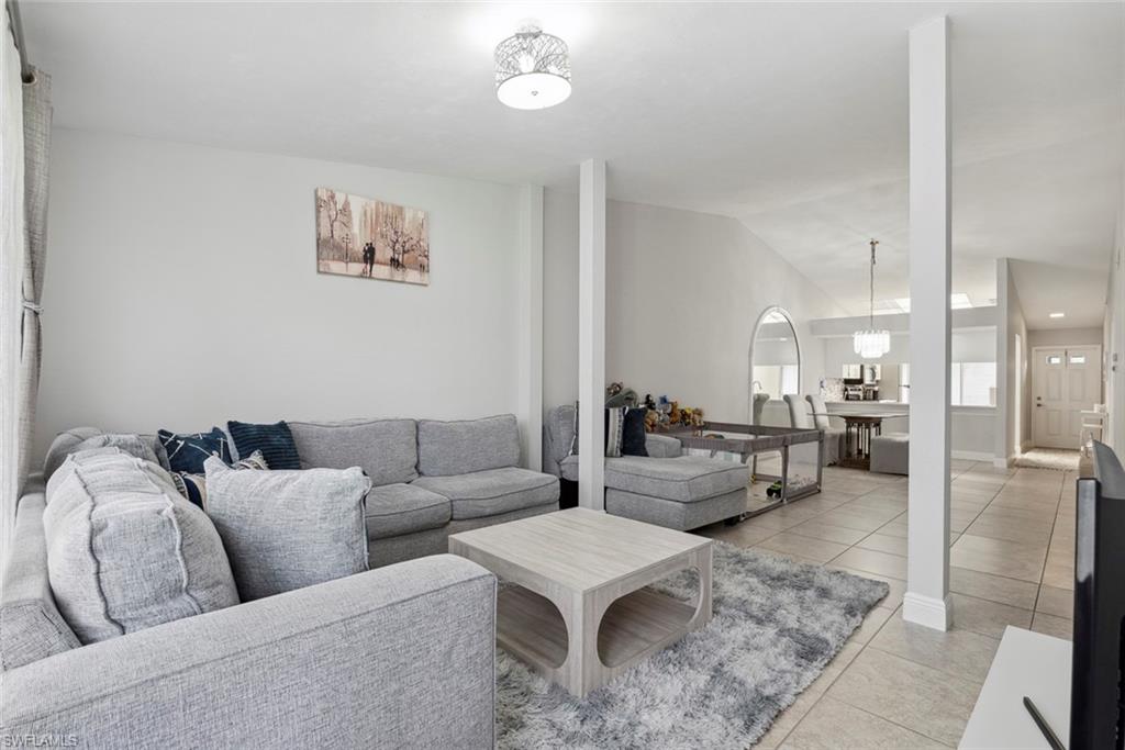3410 Frosty Way, Unit 4802 Naples, FL 34112 - Photo 8 of 27 Living room featuring light tile patterned flooring, vaulted ceiling, and a chandelier