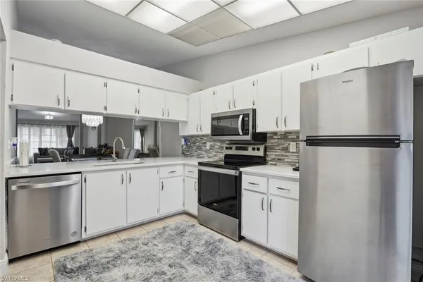 a kitchen with white cabinets stainless steel appliances and a refrigerator