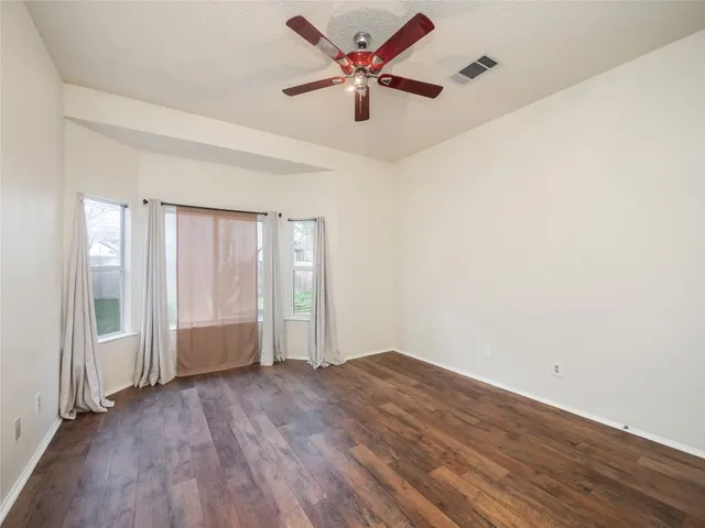 an empty room with wooden floor and windows